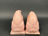 pair of pink ceramic pig bookends on a black background