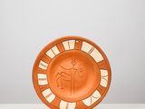 une assiette orange posée sur une table blanche, près d'un mur blanc