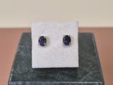 une paire de boucles d'oreilles à clous en saphir bleu posée sur un bloc de marbre