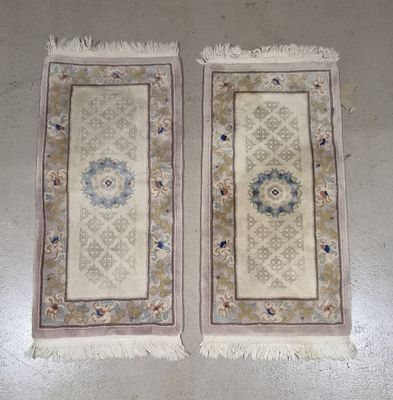 une paire de tapis orientaux à franges posés sur un sol blanc