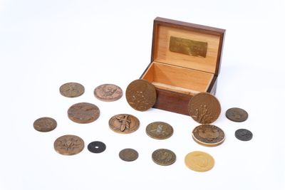 une petite boîte en bois remplie de pièces de monnaie posée sur une surface blanche