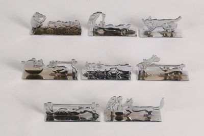 five silver metal animal figurines on display on a white surface