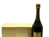 the bottle of champagne is next to a gold box on a white surface
