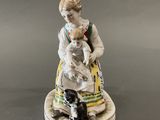 a figurine of a woman holding a child and a cat