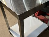 une table en métal surmontée d'une étagère, dans un entrepôt