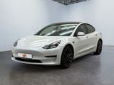 a white tesla model 3 parked in a white room