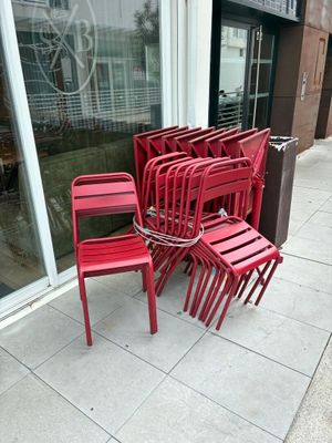 de nombreuses chaises rouges alignées sur le trottoir devant un immeuble