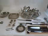 une table sur laquelle sont posés des couverts et un plateau contenant des couteaux et des cuillères