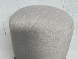 grey round footstof on a cardboard box in front of a white wall