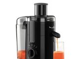 une photo d'un extracteur de jus avec un verre de jus d'orange à côté