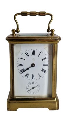 une petite horloge en laiton avec des chiffres romains sur le cadran