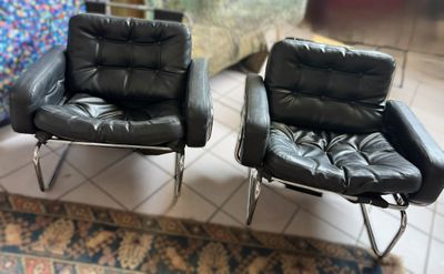 pair of black leather lounge chairs on a rug in a living room