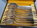 six silver spoons in a box with a yellow lining