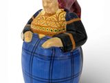 une figurine représentant un homme assis sur un tonneau