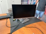 a man standing next to a desk with a computer on it