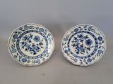two blue and white plates with floral designs on them sitting on a table