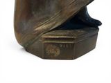 a bronze statue of a man with a hat on top of a book