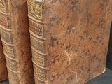 several old books are stacked on top of each other on a black surface
