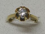 une bague en or sertie d'un diamant, posée sur une table