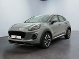 Une voiture grise est garée dans une grande pièce au sol noir.