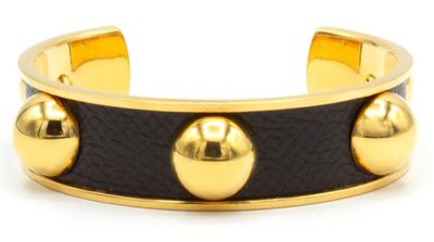 un gros plan d'un bracelet orné de boules dorées sur fond blanc