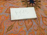 a sign on a bed with a paisley pattern on it