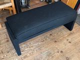 a black bench sitting on a wooden floor in a room