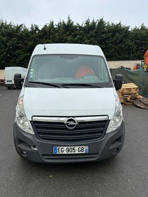 the white van is parked in the parking lot next to a pile of wood
