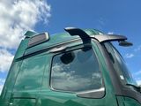 a green semi truck with its door open and a sky background