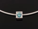 a silver necklace with a blue topaz stone on a black background