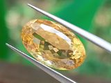 un gros plan d'un diamant jaune tenu par une paire de pinces