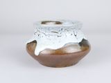 a white and brown vase sitting on a white surface