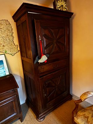 une armoire en bois placée dans un coin de la pièce, sur laquelle est posé un ordinateur