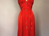 une robe rouge posée sur un mannequin adossé à un mur