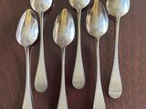 six spoons are lined up on a table with a wooden surface