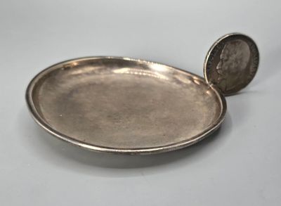 un plateau en argent posé sur une table, sur lequel se trouve une pièce de monnaie