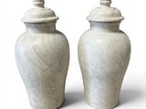 deux vases blancs posés l'un à côté de l'autre sur une surface blanche