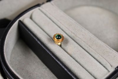 une bague en or sertie d'une pierre verte, dans un écrin