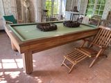 une table de billard au milieu d'une pièce où se trouvent des chaises et une table