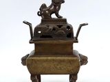 une statue en bronze représentant un chien assis sur une boîte