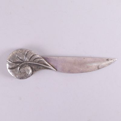 une assiette ancienne en argent, ornée d'une feuille sur un fond blanc