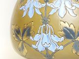a gold vase with blue flowers on it on a white surface