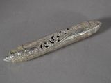 un vieux stylo en argent posé sur une table, à côté d'une feuille de papier