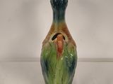 a green and orange vase with a bird on it