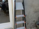 une échelle appuyée contre un mur, à côté d'une table de terrasse
