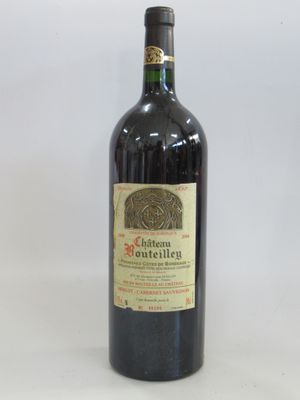 an old bottle of red wine sitting on top of a white table