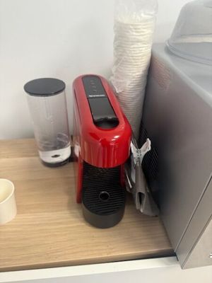 une cafetière rouge posée sur un plan de travail, à côté d'un mixeur
