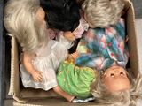 trois poupées dans une boîte en carton posée par terre