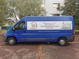 a blue van parked in a parking lot with trees in the background