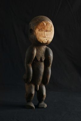 une vieille sculpture en bois représentant un homme debout, les mains sur les hanches
